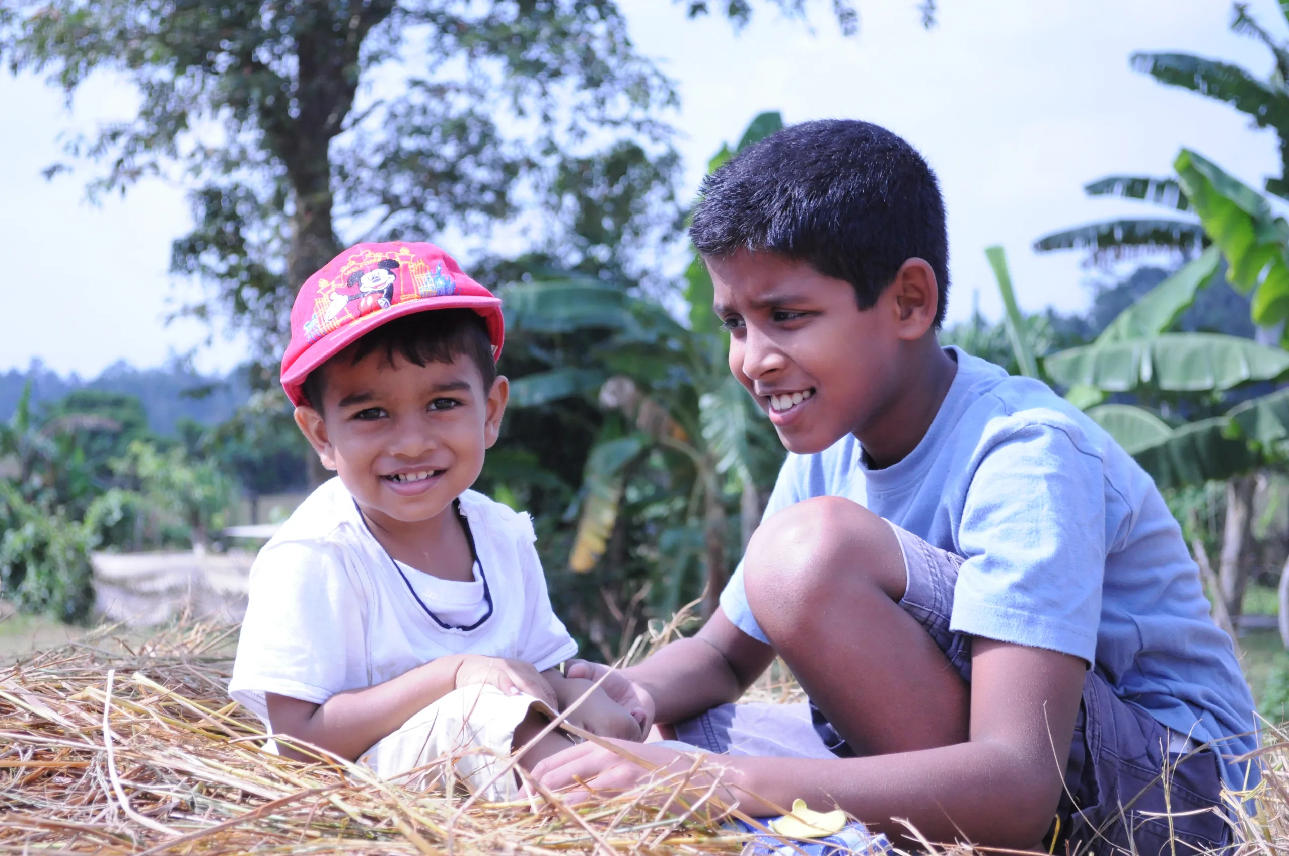 Two children sitting together on a haystack